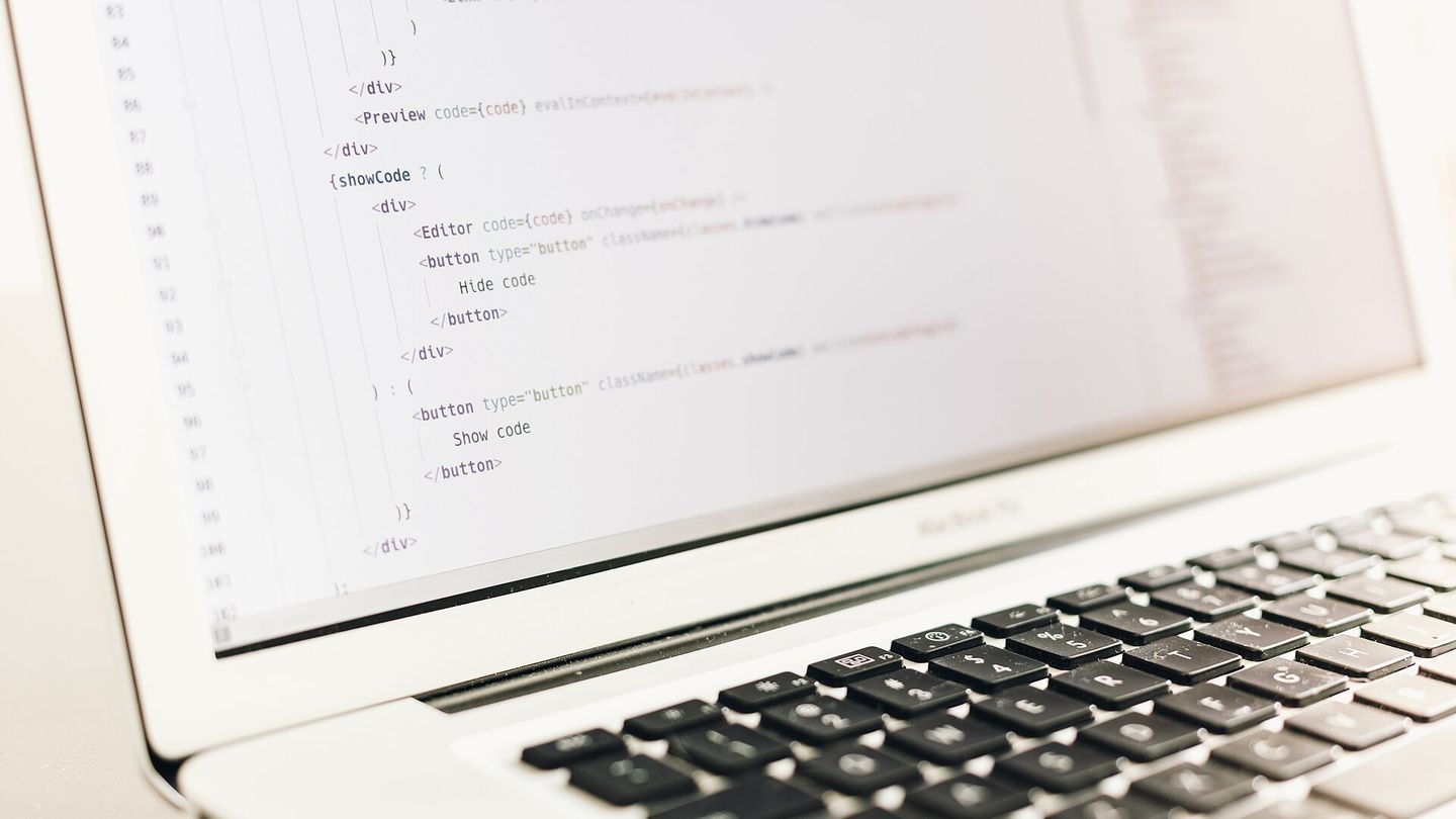 Quellcode in einem Editor auf dem Bildschirm eines aufgeklappten Laptops