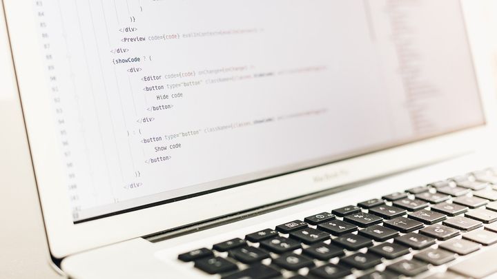 Quellcode in einem Editor auf dem Bildschirm eines aufgeklappten Laptops